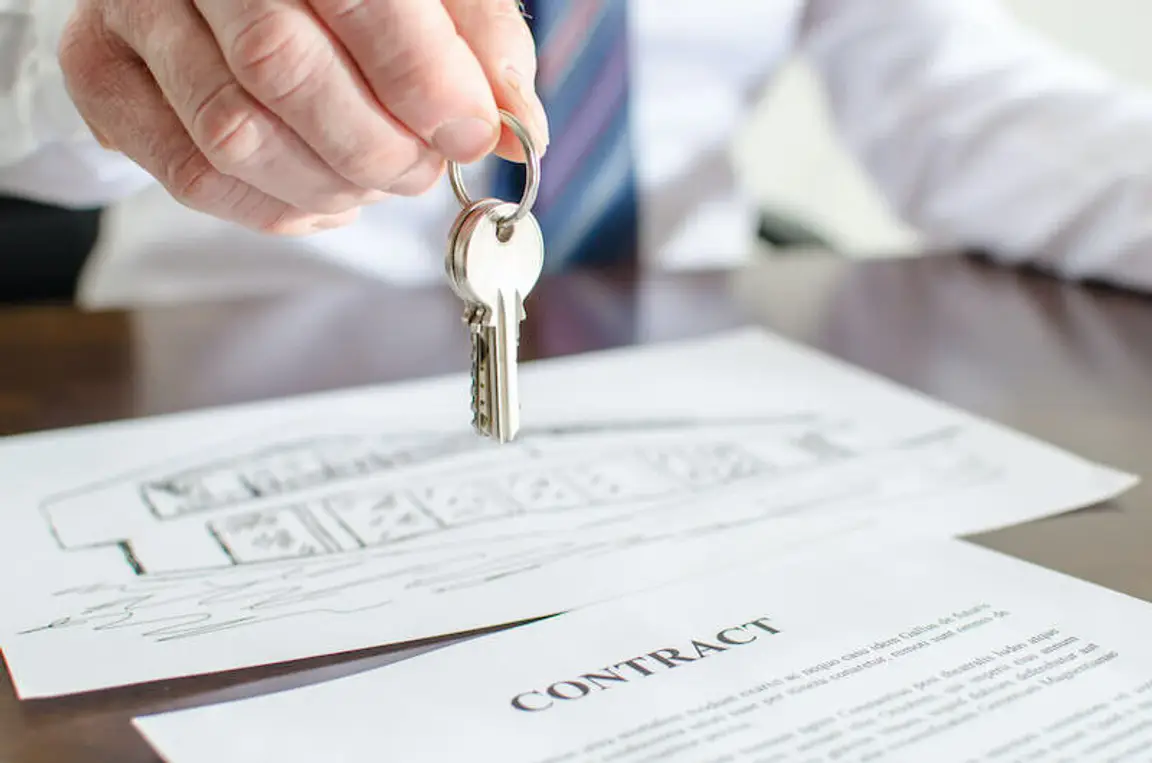 cash buyer holding house keys over a contract