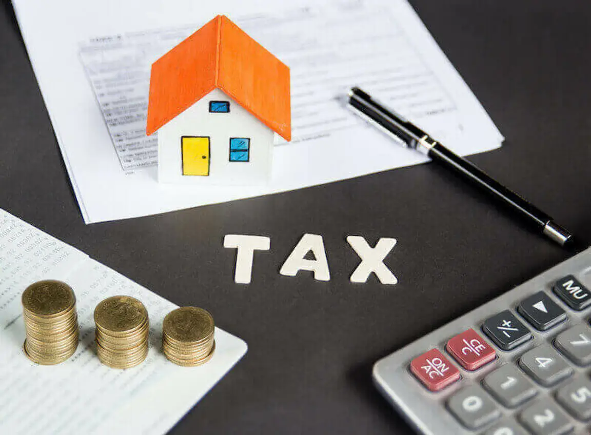 model house, coins and calculator on a table - tax when you sell a house in Memphis