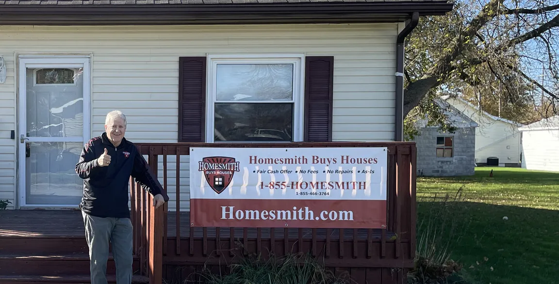 Barry Smith, Homesmith founder/CEO, in front of recently purchased house with thumbs up