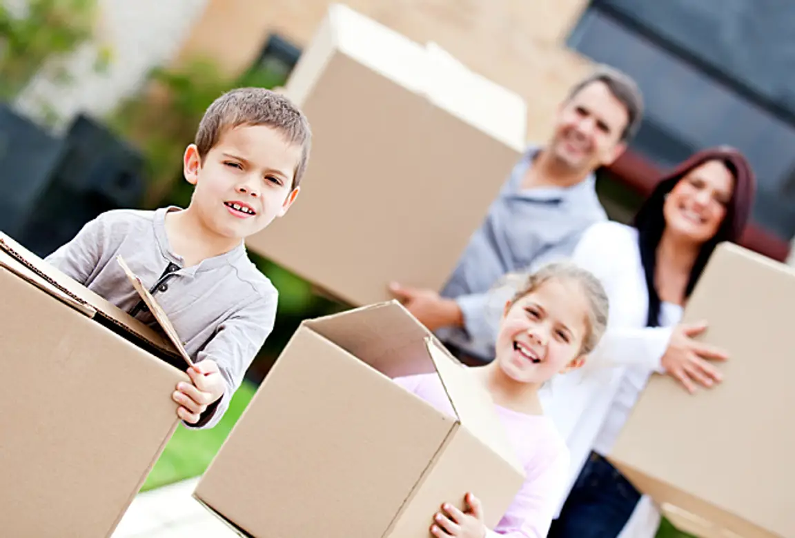 Family moving home and carrying cardboard boxes