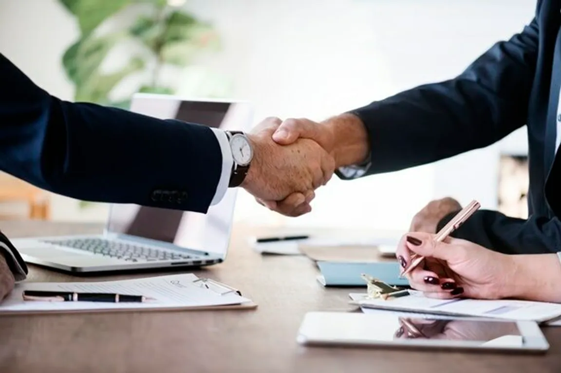note buyer and seller shaking hands, completing owner financed sale