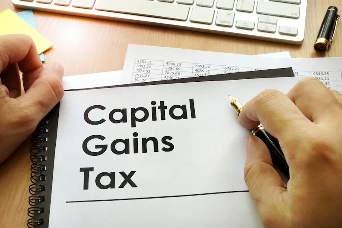 Hands holding documents with title capital gains tax text