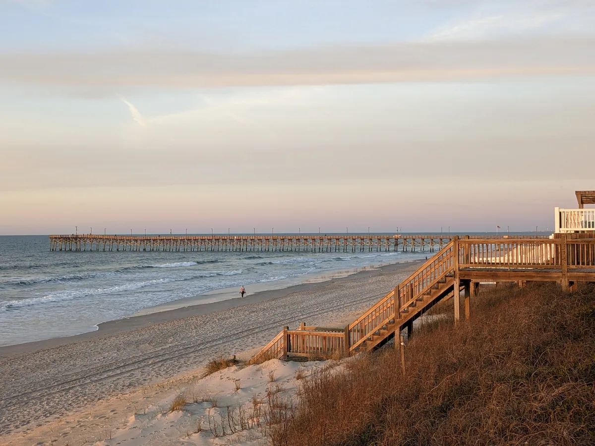 Wooden beach access stairs over the dunes with the Surf City pier in the distance