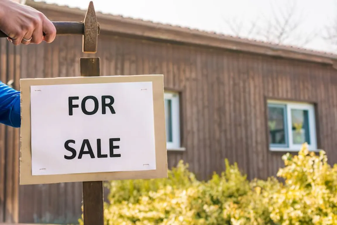 House with for sale sign in front yard