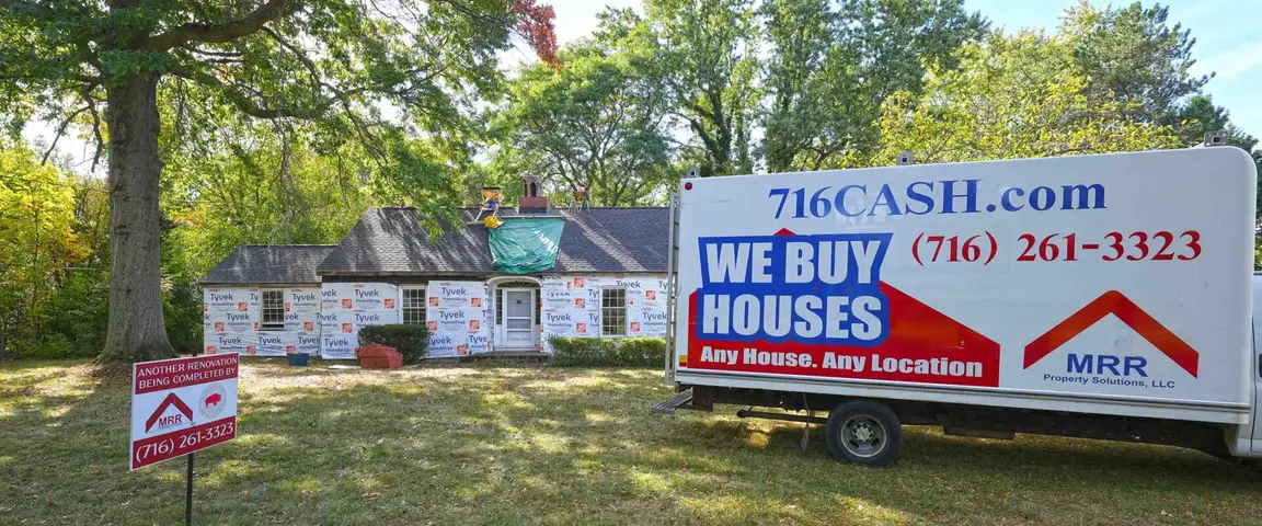 MRR Property Solutions renovation project on a brick home in Buffalo, NY, showing construction vehicles and exterior updates in progress.