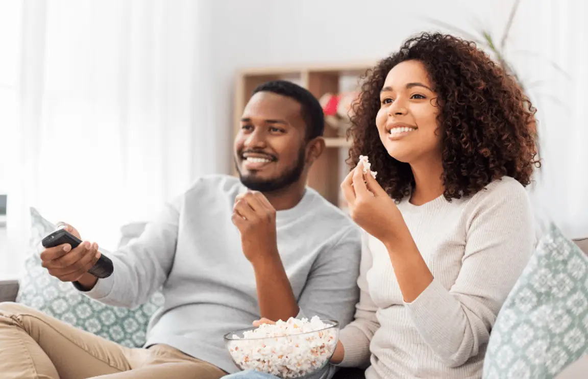 Two young homeowners eat popcorn while watching some of the best HGTV home renovation shows