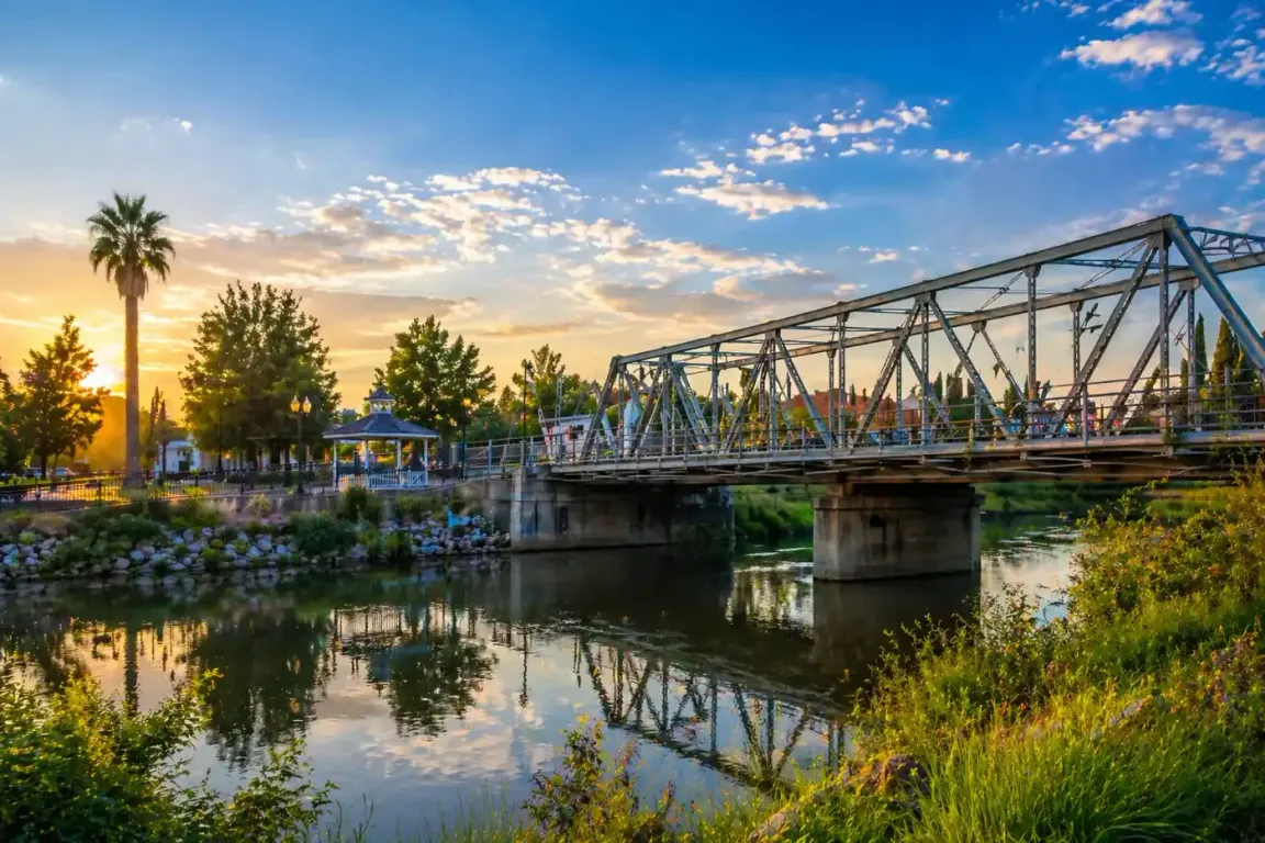 Scenic river view with bridge and trees at sunset in Yuba City CA, quiet neighborhood where we buy houses and help homeowners sell their house fast