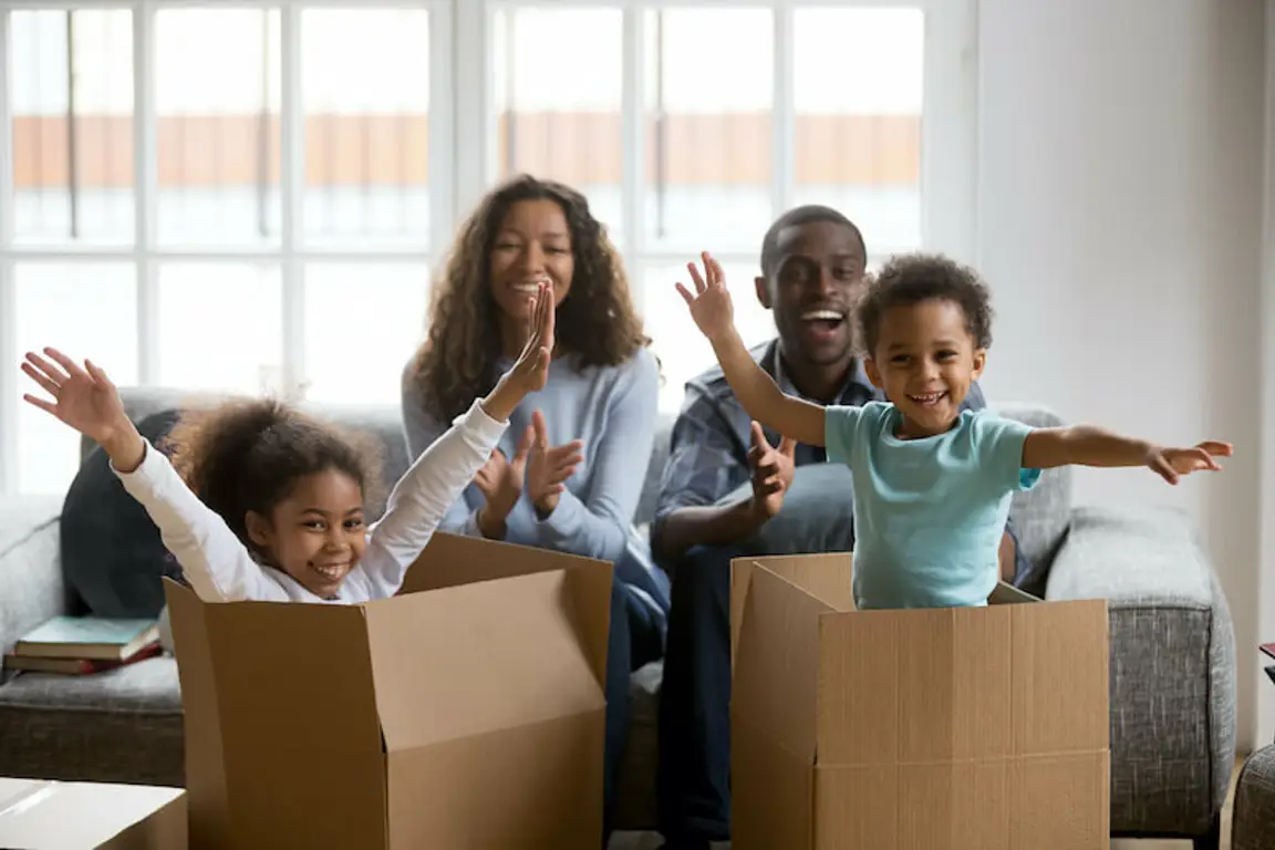 Happy african american parents and kids playing in boxes moving out of Houston