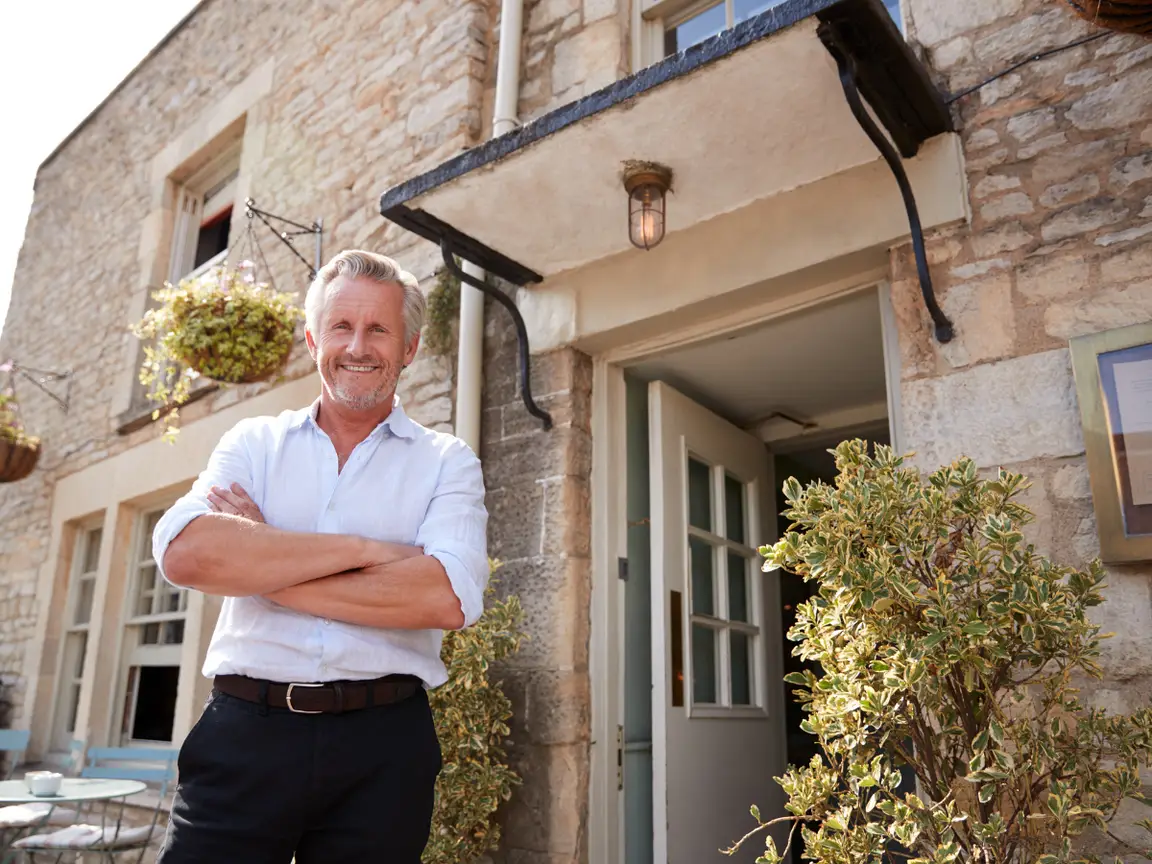 A landlord standing in front of the open door of a stone-faced rental property
