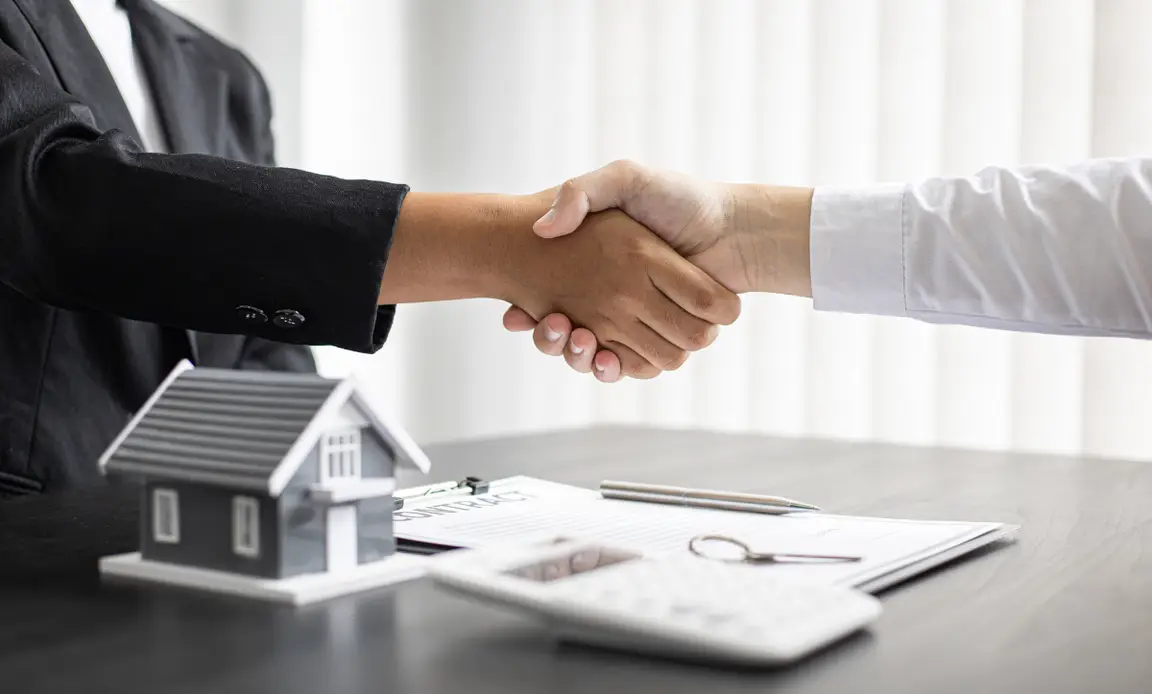 Hands shaking over a home sale contract