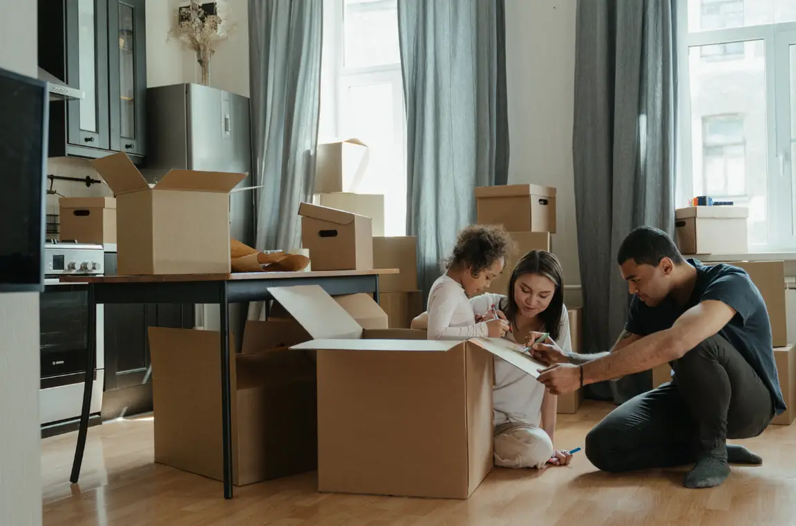 A mother, father, and daughter labeling boxes while moving.