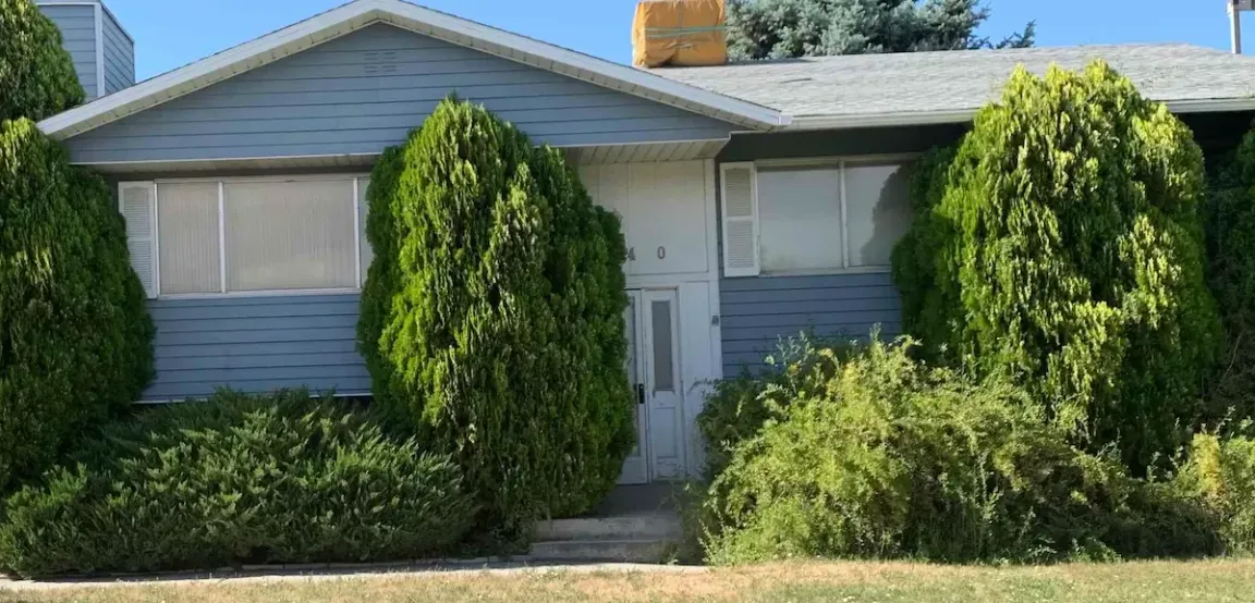Modest single-family brick home in Salt Lake City with a 'For Sale' sign, representing foreclosure relief services.
