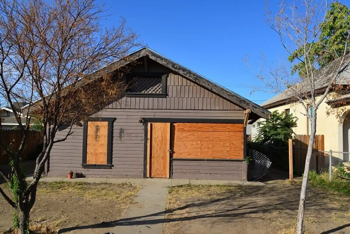 A reacently condemned house with cardboards on its windows and door frames