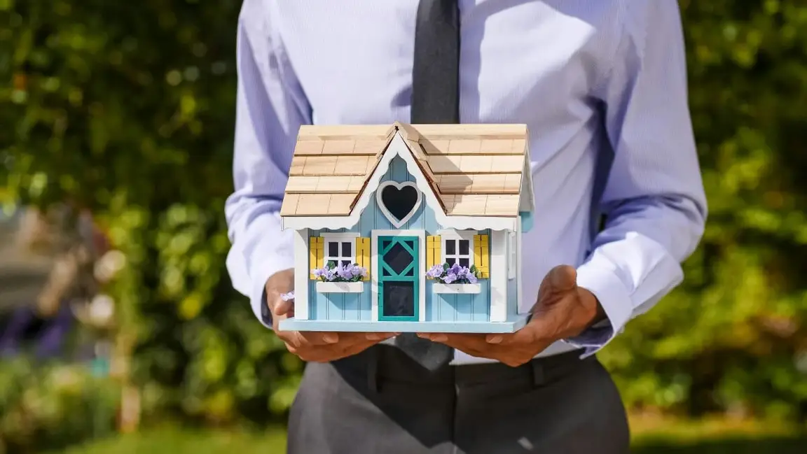 Person holding a model home outdoors, illustrating moving forward after inheriting a property you do not plan to keep.