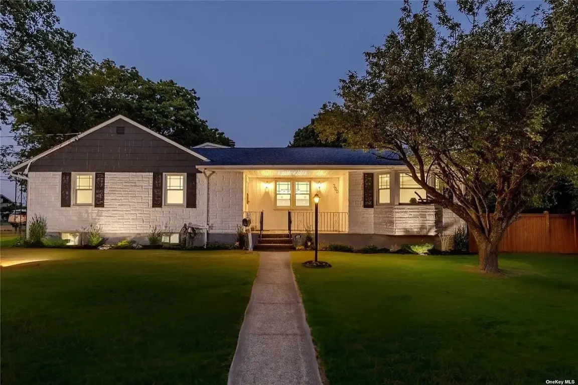 Single story home in Long Island lit up at dusk with a walkway leading to the front door