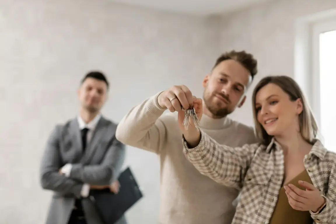 Couple receiving house keys from a real estate agent, illustrating selling a house with tenants without legal headaches.