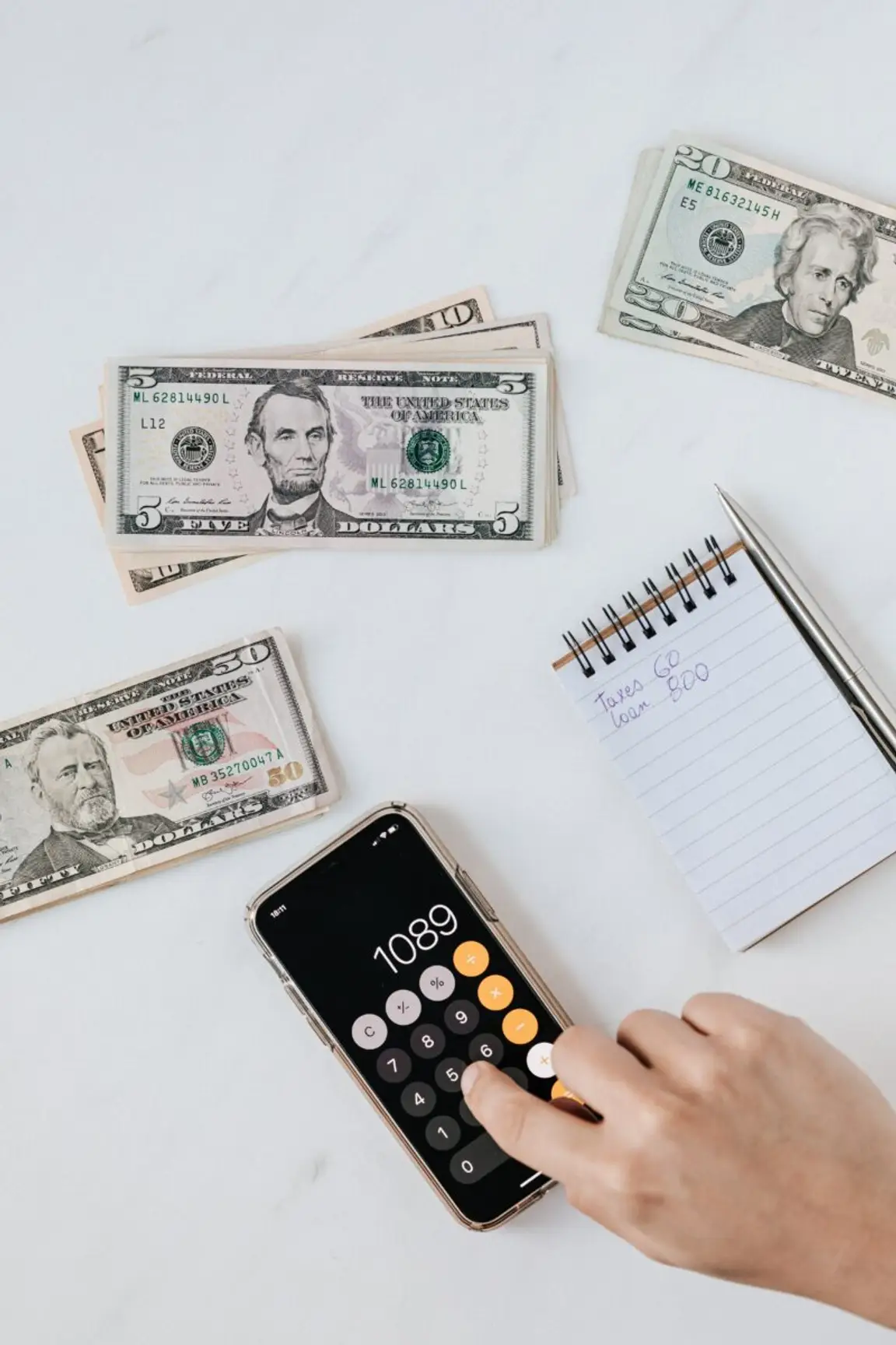 A Notepad, Money Bills, and a Hand Over a Phone | Blogs About Houses