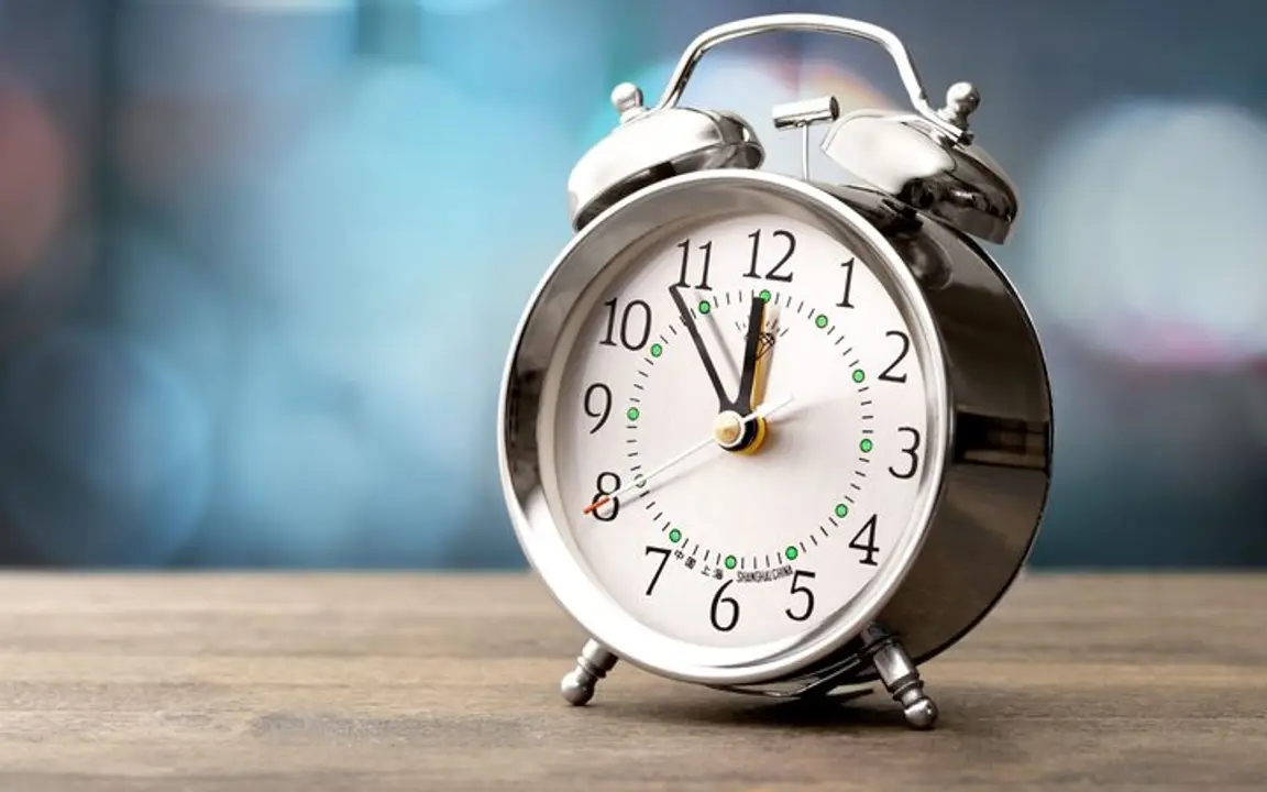 an old school chrome alarm clock pointing to 11:54