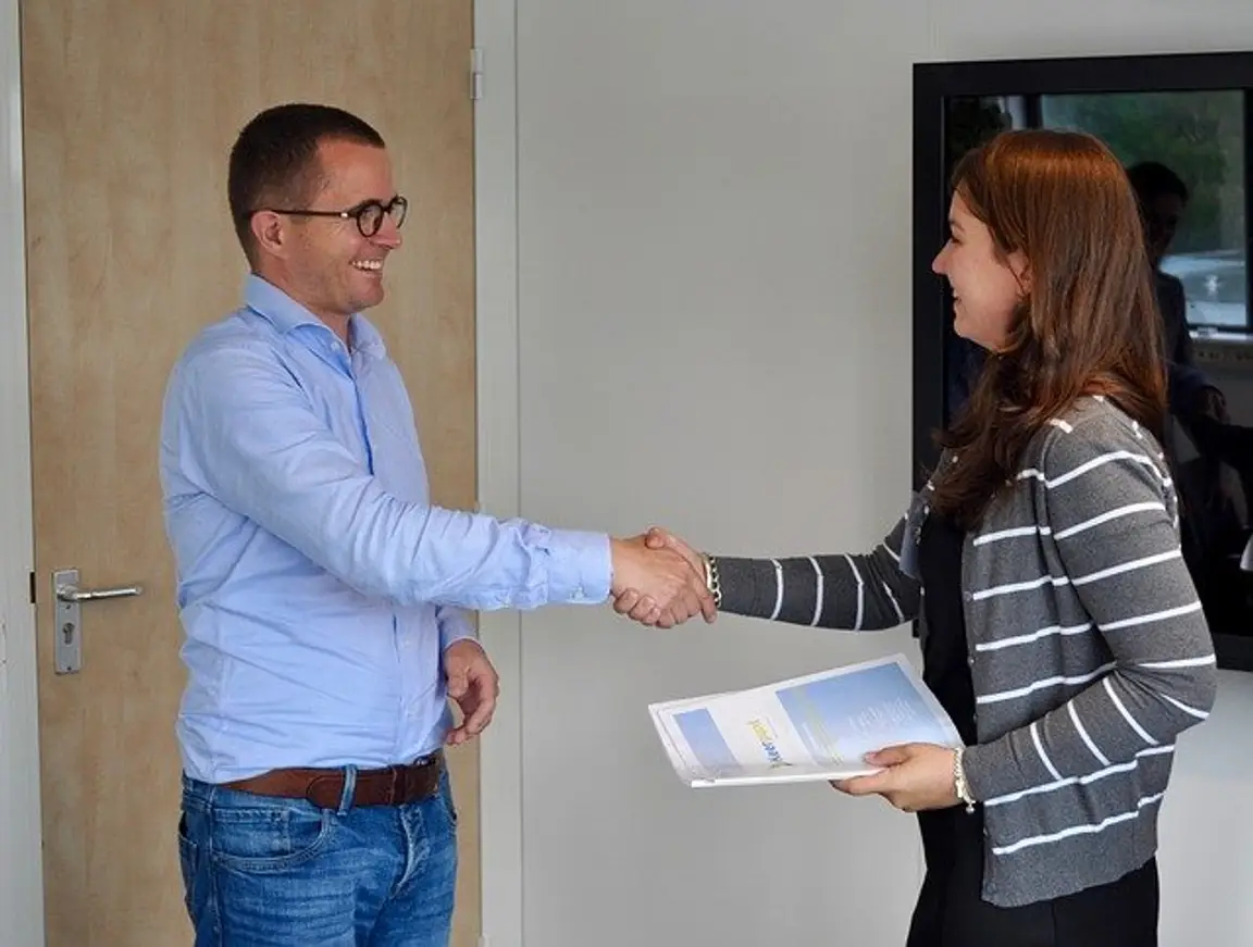 two people shaking hands with one holding a folder