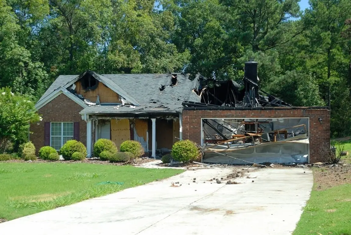 a partially damaged house with the garage door missing