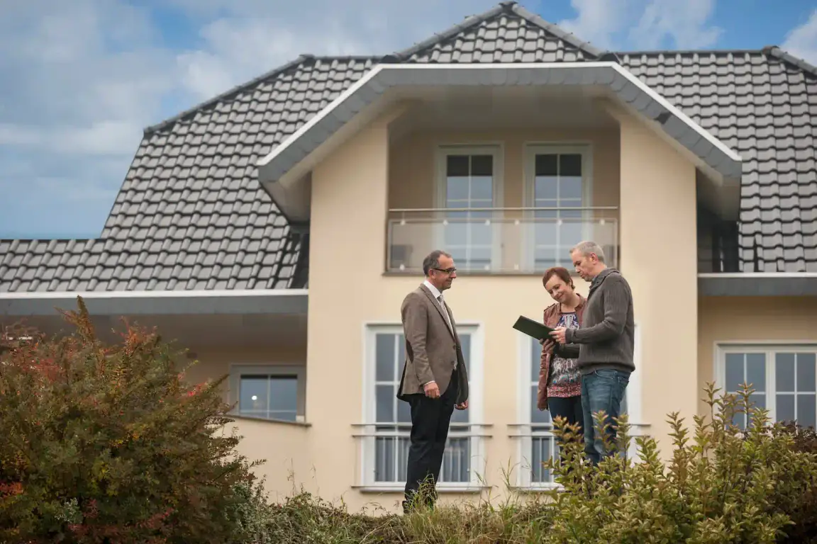 Estimate agent with potencial buyers in front of house