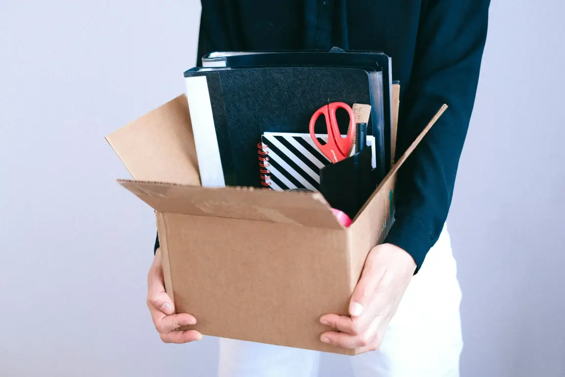 Person packing office belongings into a moving box.