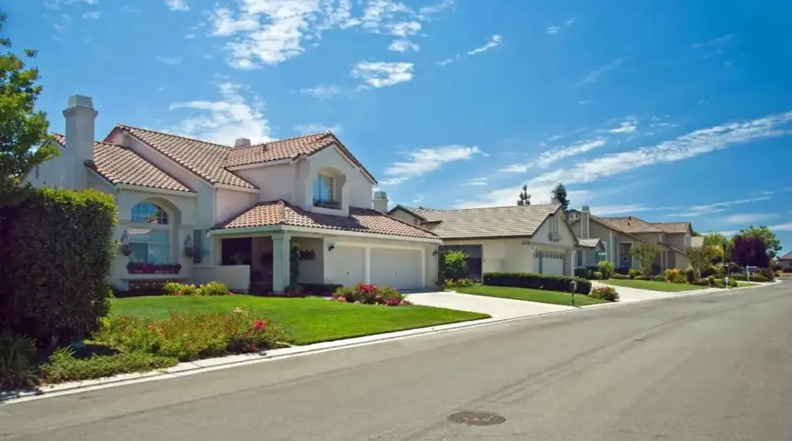 Large suburban homes with asphalt shingles and green lawns in daytime