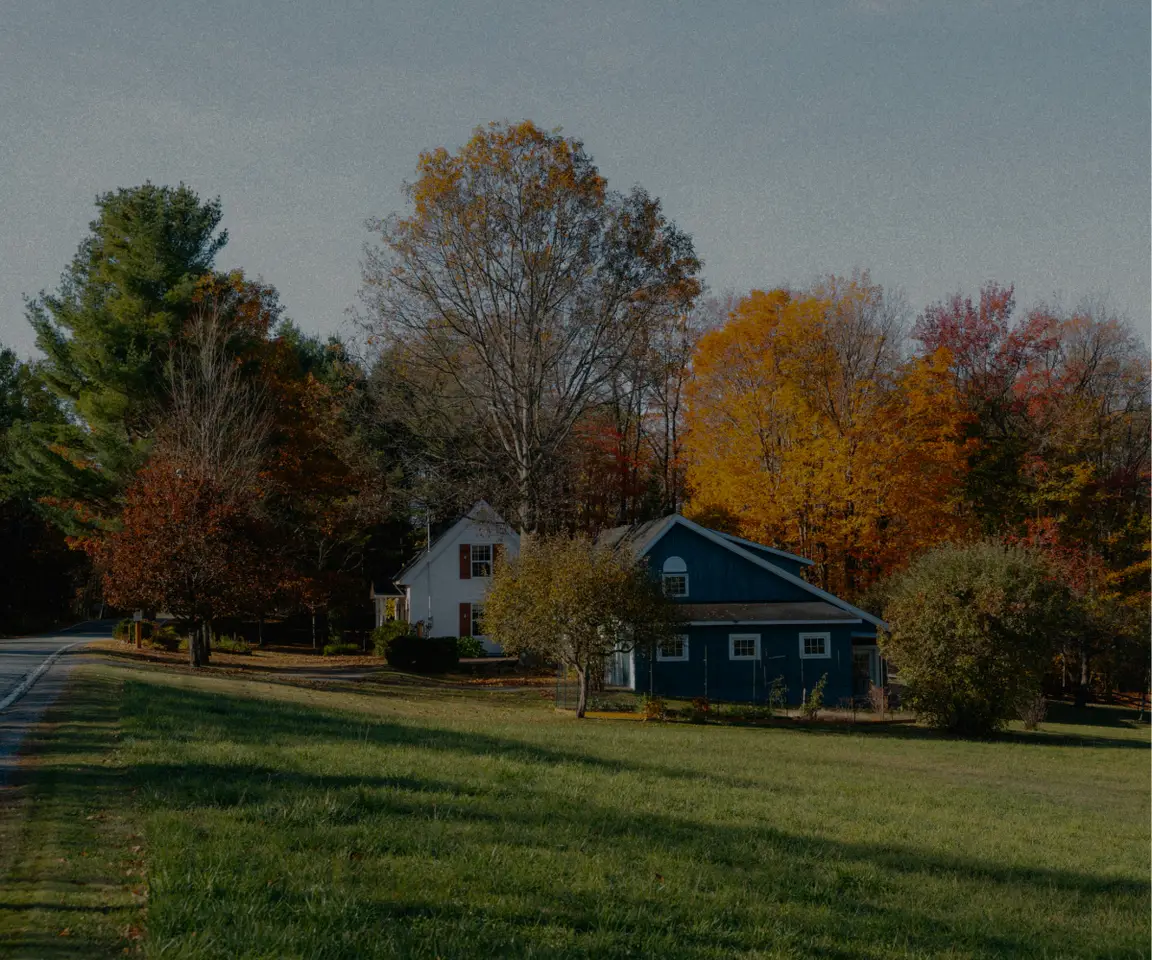 Rural home surrounded by colourful autumn trees and a spacious green lawn.