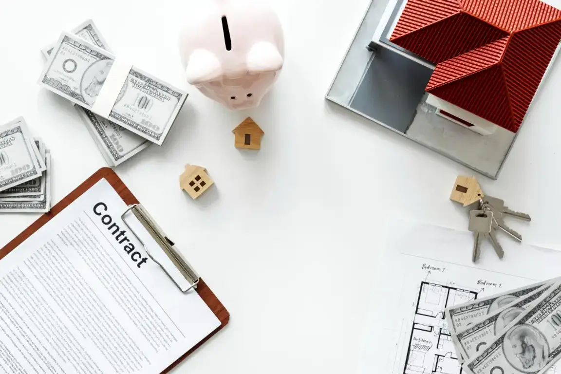 Contract, a miniature house and some coins on the table