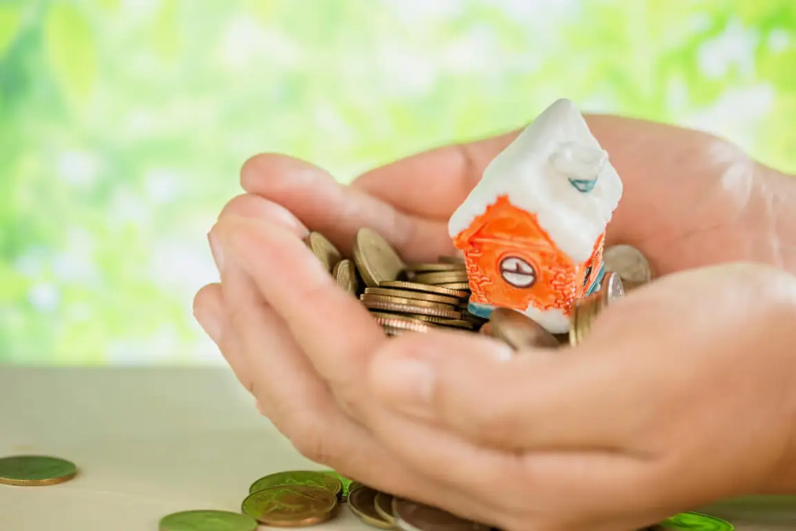 Hand holding a house and some coins