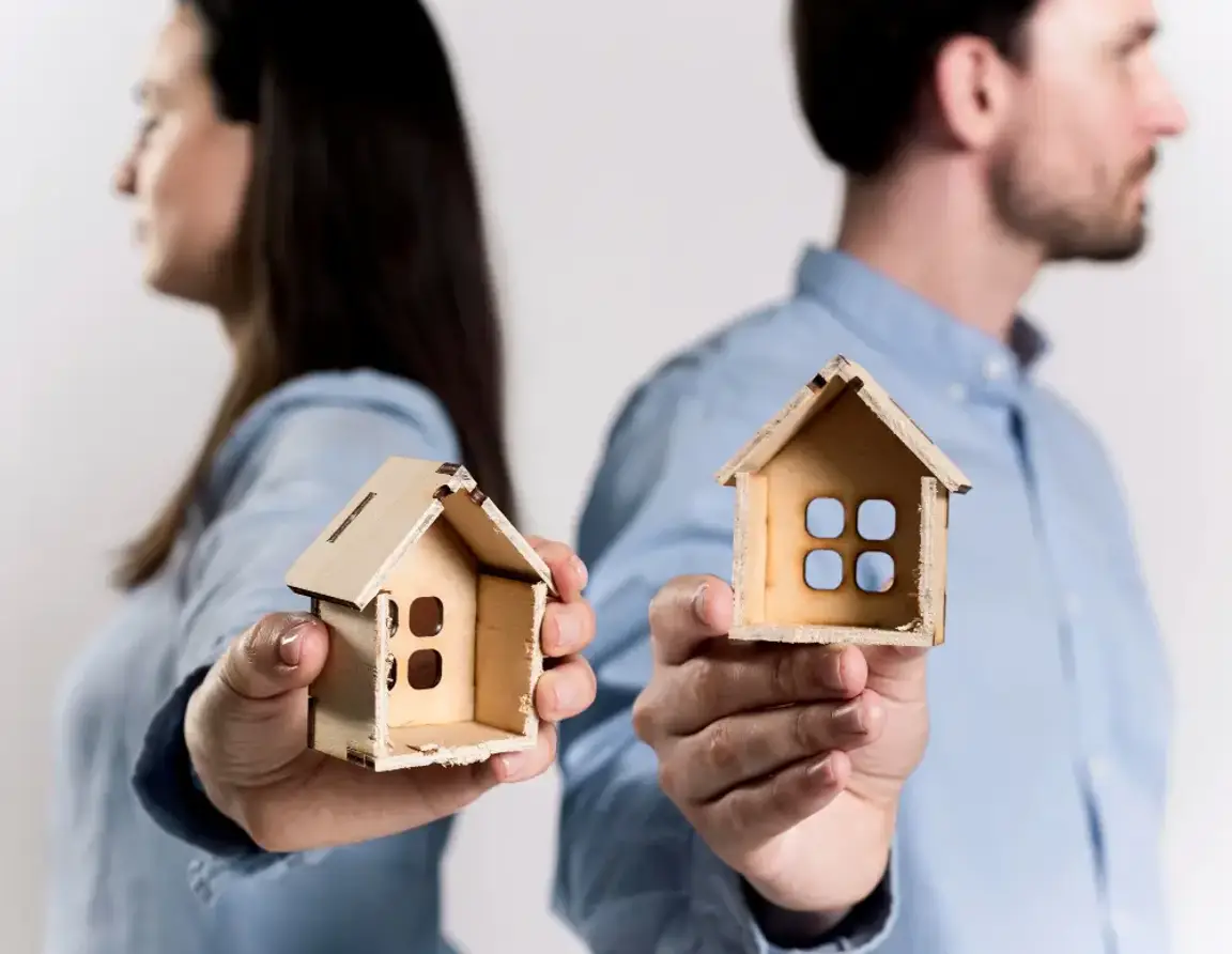 People holding 2 houses made of cardboard