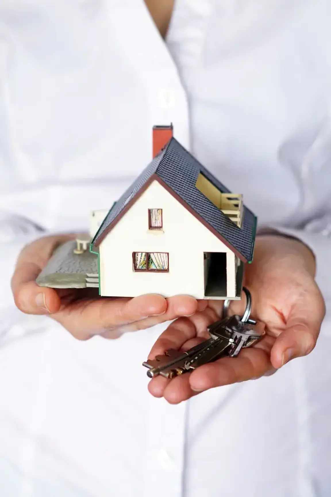 man holding a miniature house and key