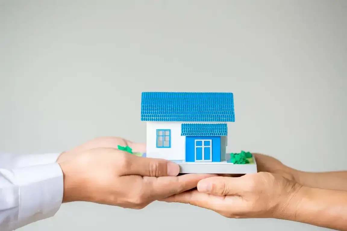 A man handing another man a miniature house