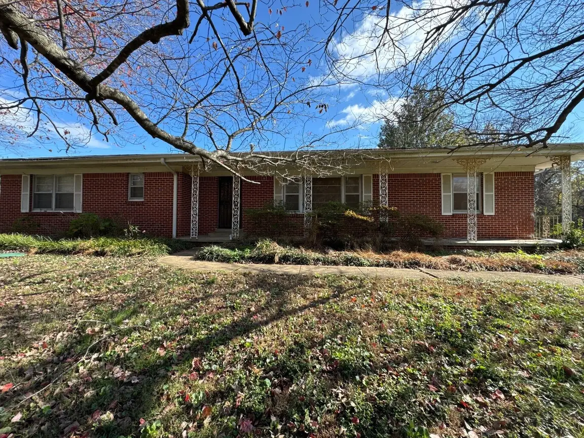 Red brick ranch home in Tennessee with an overgrown front yard, the kind of as-is property Steadfast Home Buyers buys for cash