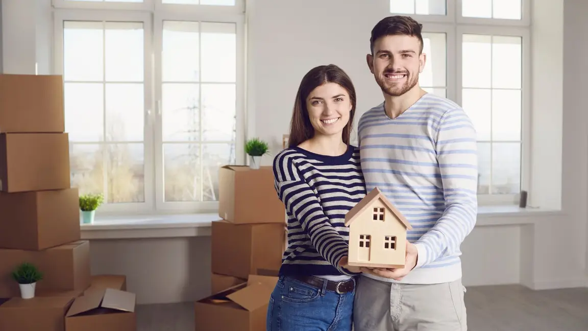 A couple holding a miniature house on their hands
