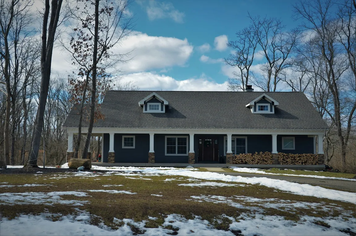 White and brown house behind bare winter trees