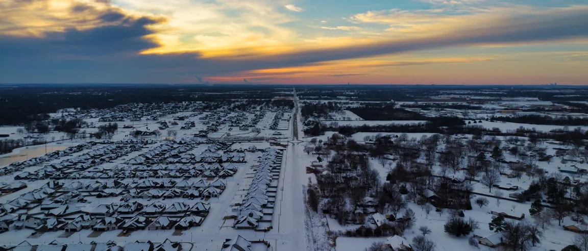 Snow-covered suburban neighborhood at sunset