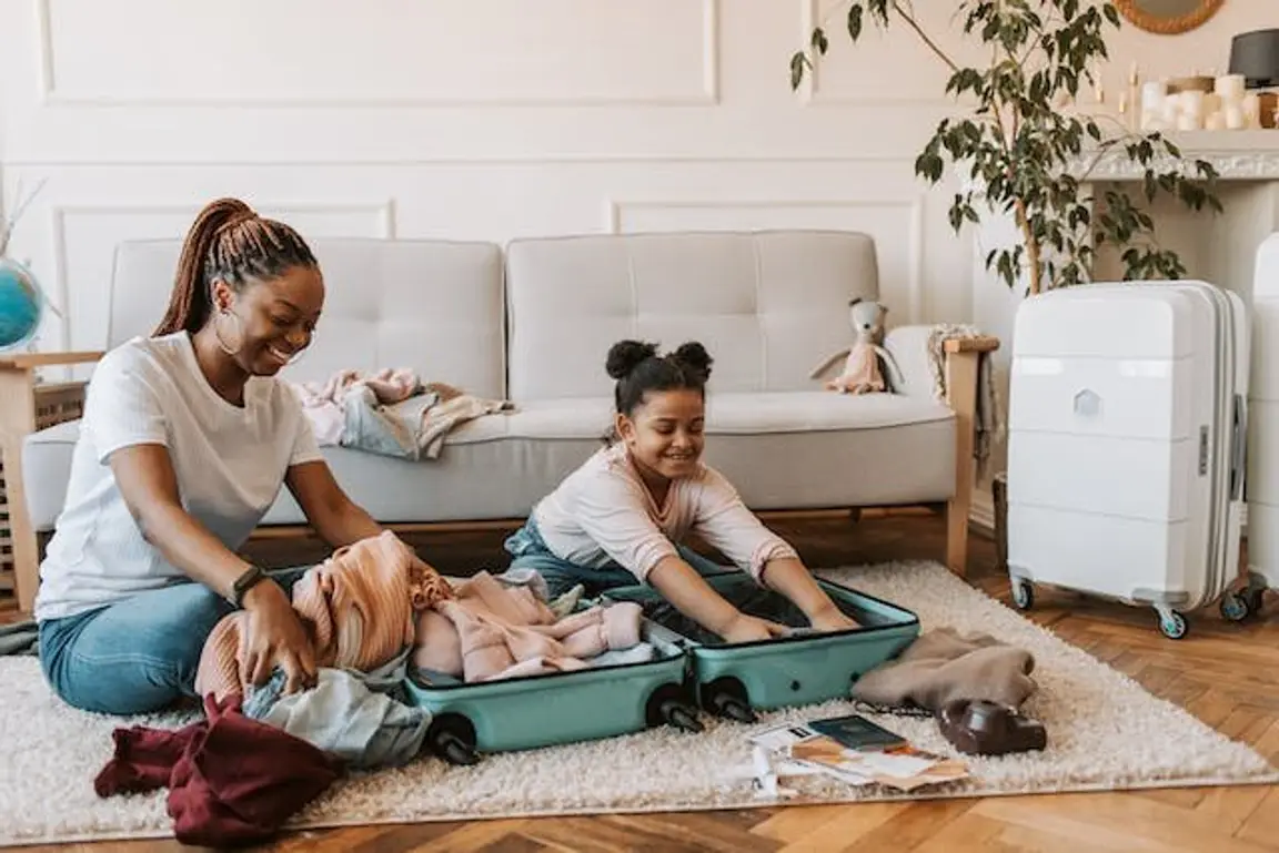 Mother and daughter packing clothes as they move.