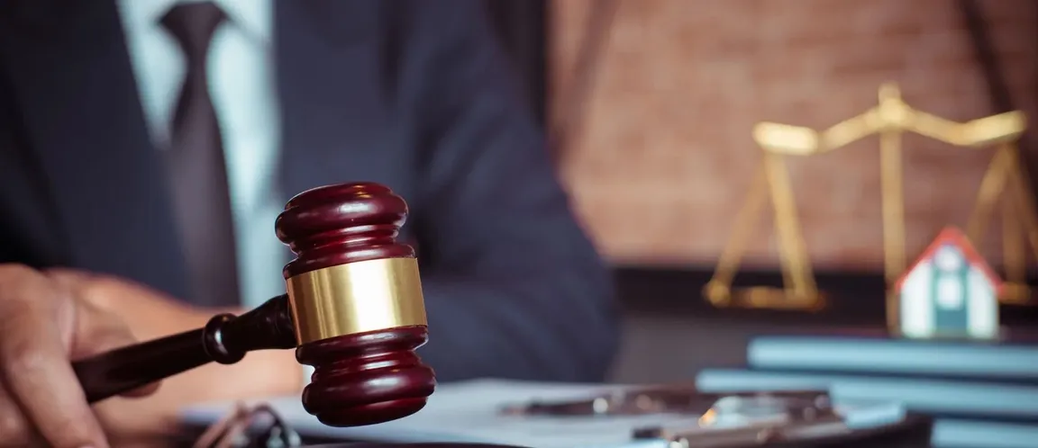 judge’s gavel on desk with house model and scales of justice representing foreclosure process