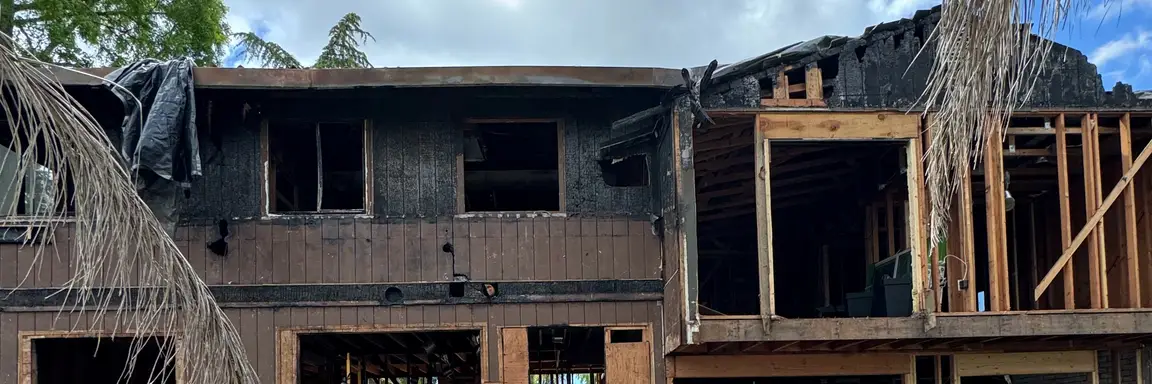 Two-story home with extensive fire damage and exposed framing awaiting major repairs.