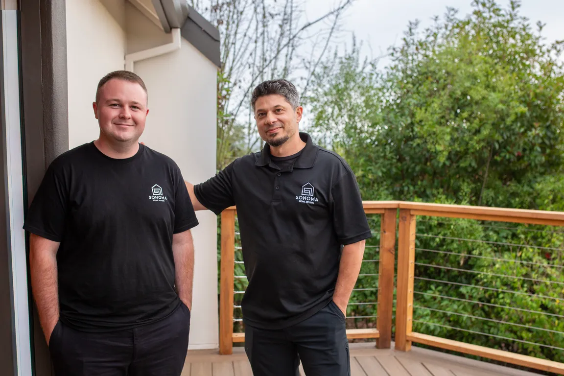 Brian Kraut and Wyatt Postal of Sonoma Home Buyers on a residential deck in Sonoma County, wearing branded shirts with trees in the background.