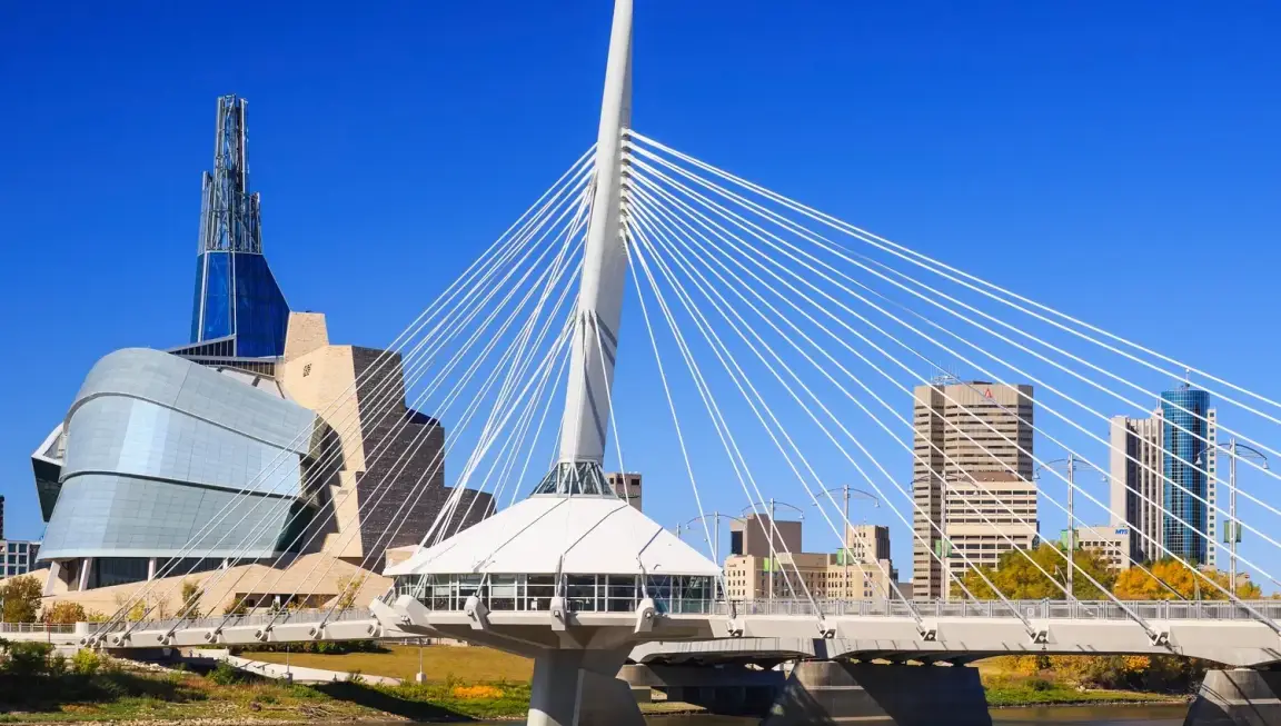 Winnipeg skyline featuring Esplanade Riel pedestrian bridge and Canadian Museum for Human Rights on a clear day in downtown Winnipeg Manitoba