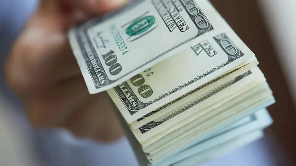 handing over a stack of 100 dollar bills to buy a house