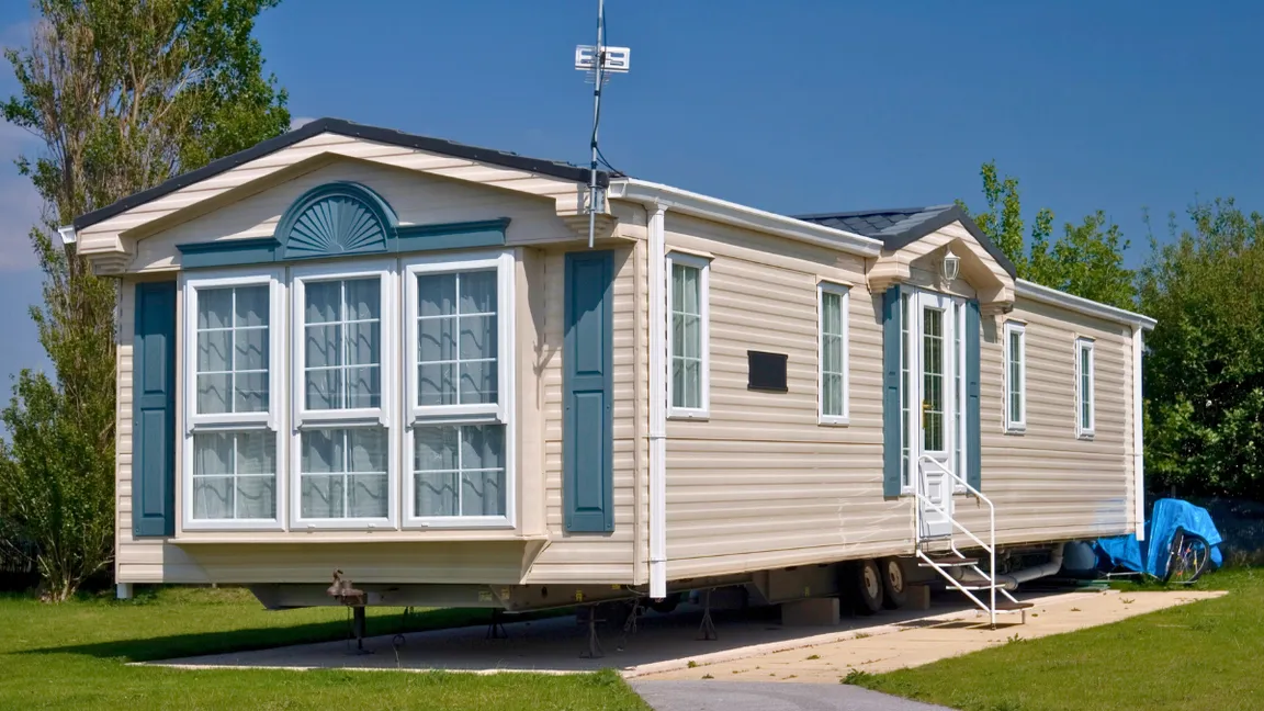 A tan singlewide mobile home for sale at a mobile home store