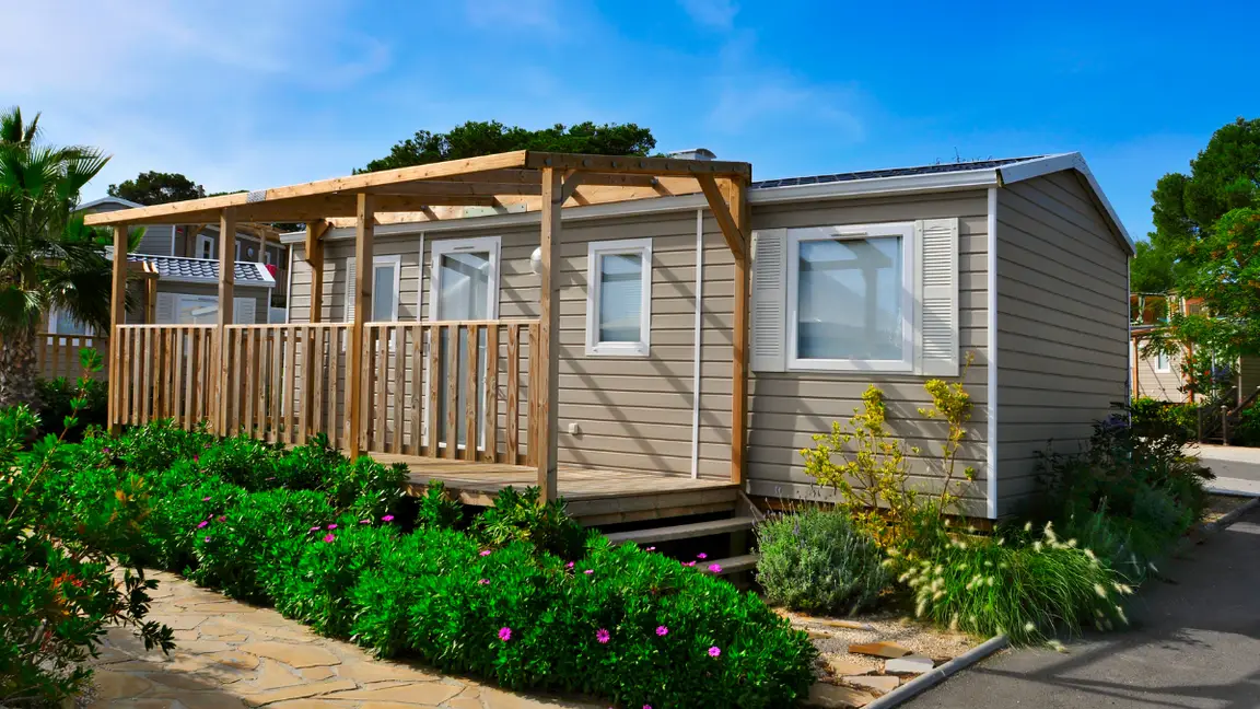 A singlewide trailer with a porch and landscaping