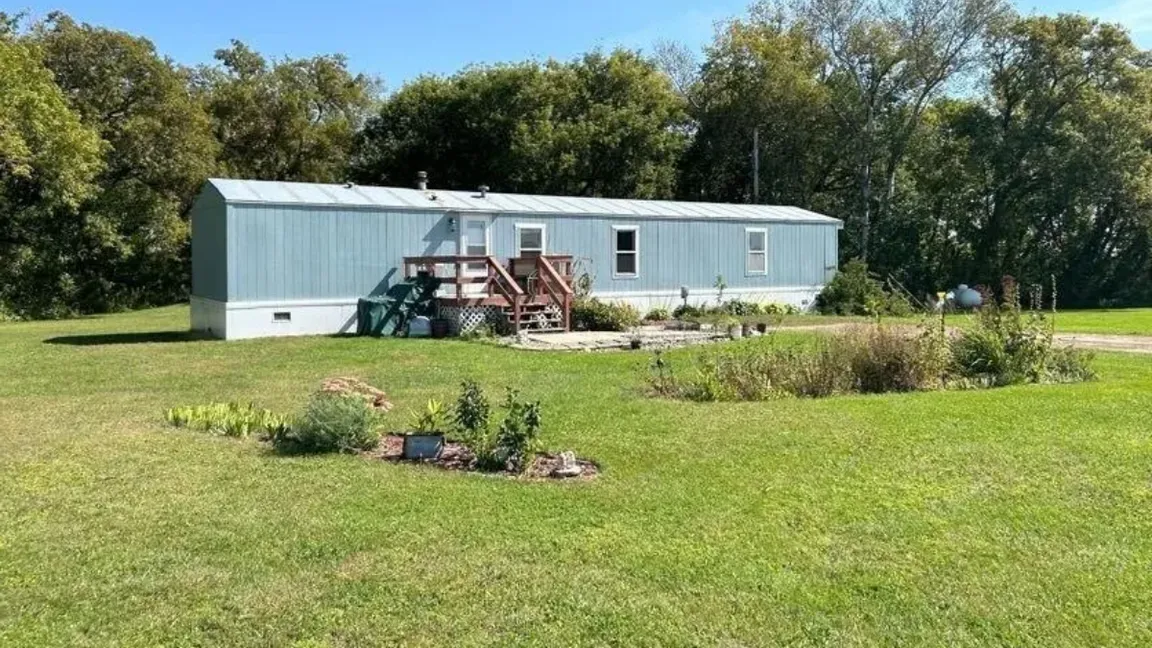 A gray singlewide mobile home on land for sale