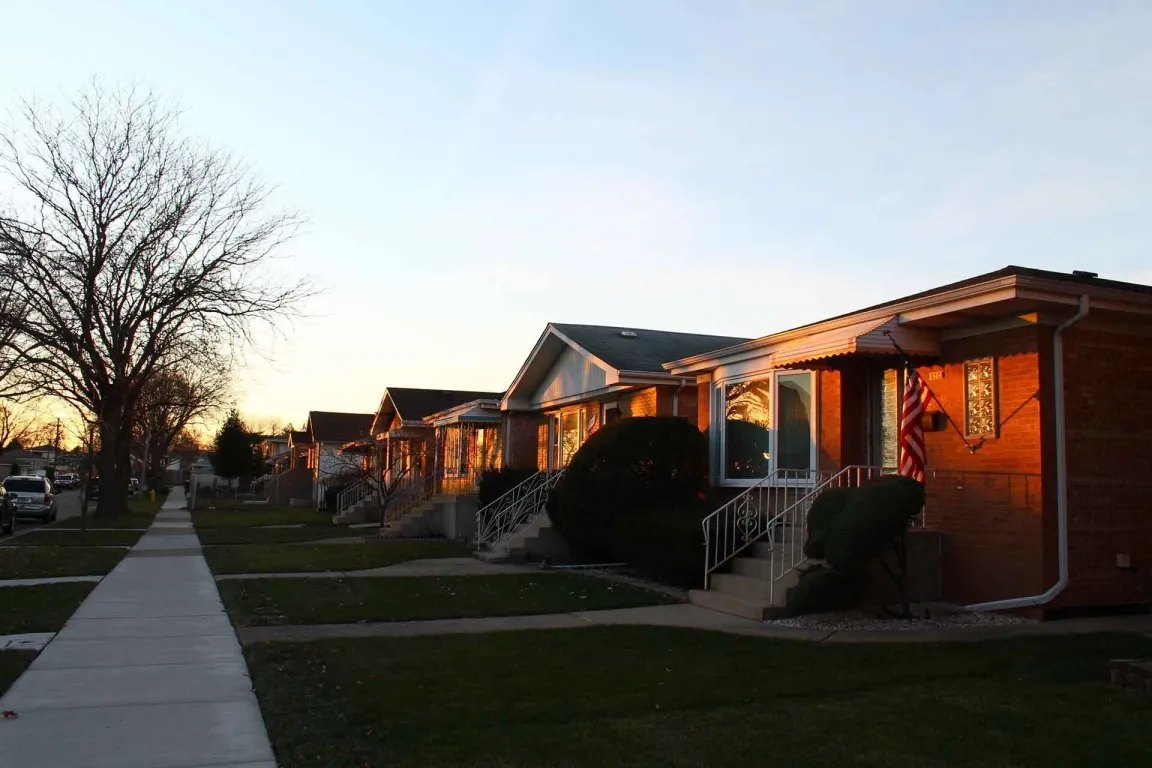 Row of suburban houses at sunset with well-maintained lawns.
