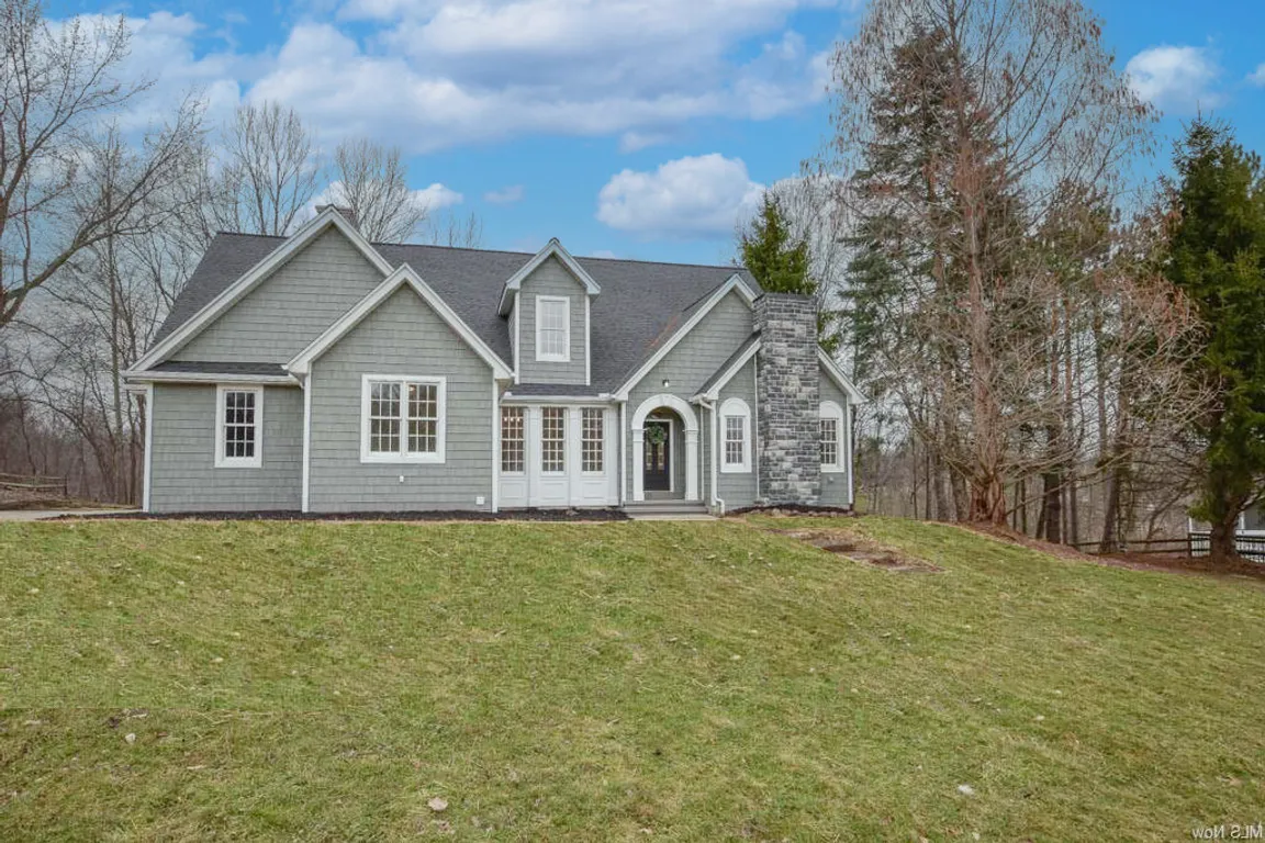 Grey house with stone chimney and white trim