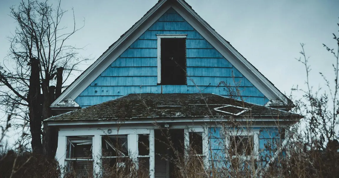 Weathered vacant house with overgrown yard, similar to vacant houses in Xenia, Ohio
