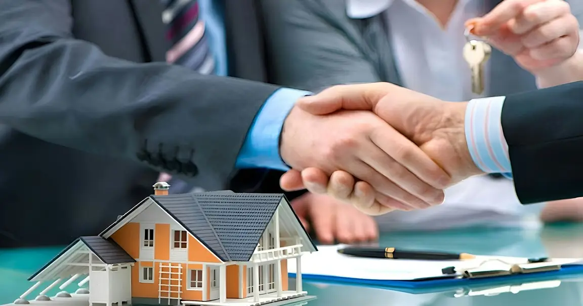 Handshake over a house model and keys after a cash home sale in Springfield, Ohio